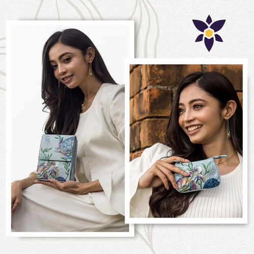 Two side-by-side photos of a woman in a white outfit holding a floral-patterned handbag. The left photo shows her seated and looking at the camera, while the right photo shows her smiling and looking away. This Bundle of Triple Compartment Crossbody Organizer with Medium Zip Pouch - 412-1107 by Anuschka features hand-painted original artwork that adds an elegant touch.
