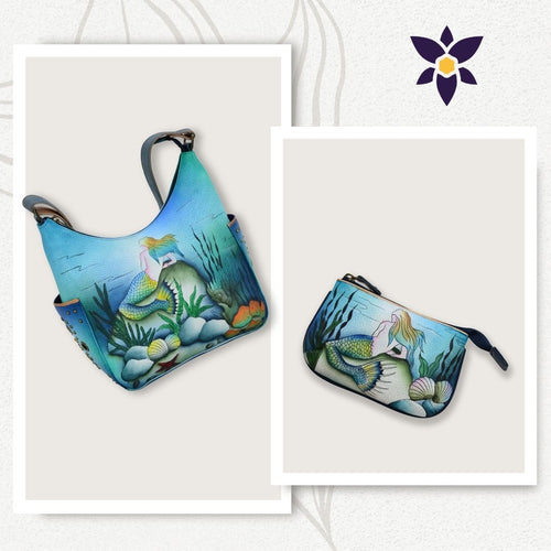 A Bundle of Classic Hobo With Medium Zip Pouch - 433-1107, both featuring an illustrative mermaid design, are displayed against a white background with a floral logo in the top right corner. Each piece is crafted from genuine leather and showcases hand-painted original artwork by Anuschka.