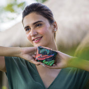 Woman displaying a colorful hand-painted embroidered Anuschka coin pouch - 1031 outdoors.