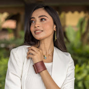 Woman with thoughtful expression wearing a white blazer and Anuschka's Adjustable Genuine Leather Wrist Band - 1176.
