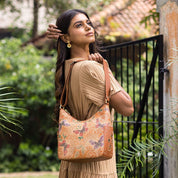 A woman poses with an Anuschka Classic Hobo With Studded Side Pockets - 433, adjusting her hair and looking away contemplatively.