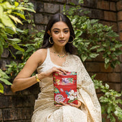 A woman posing with an Anuschka Mini Double Zip Travel Crossbody - 448 against a brick wall and leafy background.