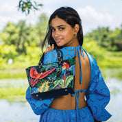 Woman holding a hand-painted, colorful Anuschka Medium Tote - 693 outdoors.