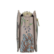 Side view of a beige Anuschka Triple Compartment Crossbody tote bag with a floral design.