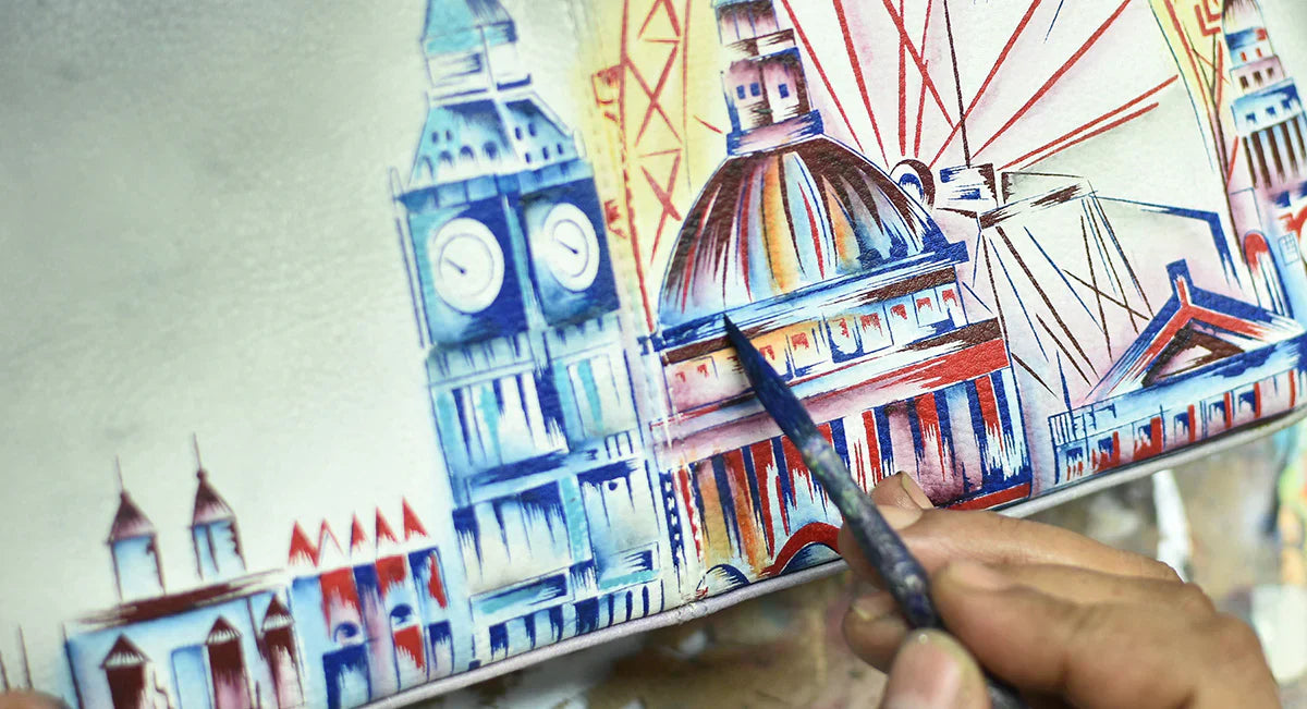 A person is painting a cityscape featuring iconic buildings, including a clock tower and a domed structure, using vivid blues and reds.