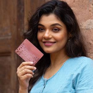 Woman holding a Anuschka Credit Card Case - 1032 made of genuine leather with card slots while smiling at the camera.