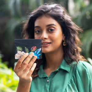Woman holding an Anuschka Credit Card Case - 1032 with a floral design near her face.