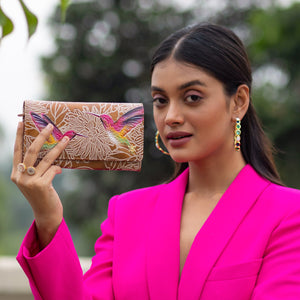 A woman in a pink blazer holding an Anuschka Accordion Flap Wallet - 1112, patterned with a butterfly design and featuring RFID protection.