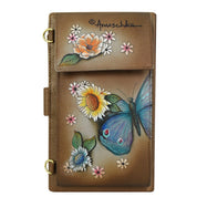 The Anuschka Cell Phone Case & Wallet - 1113 is a brown leather accessory adorned with hand-painted floral and butterfly designs, showcasing sunflowers, daisies, and a large blue butterfly. The brand's signature "Anuschka" is prominently displayed at the top. This elegant piece also serves as a smartphone case for added functionality.