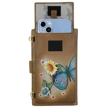 Load image into Gallery viewer, The Anuschka Cell Phone Case &amp; Wallet - 1113 is a versatile brown leather wallet adorned with exquisite floral and butterfly designs. It doubles as a smartphone case, securely holding a blue phone. The pouch features a beautifully patterned floral interior lining and is fastened with black Velcro straps.
