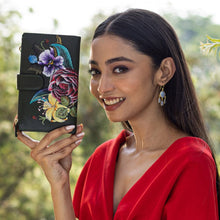 Load image into Gallery viewer, A woman in a red outfit smiling and holding an Anuschka floral-decorated Cell Phone Case &amp; Wallet - 1113.
