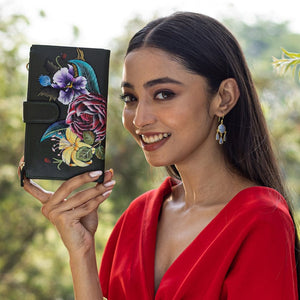 A woman in a red outfit smiling and holding an Anuschka floral-decorated Cell Phone Case & Wallet - 1113.