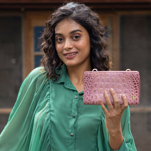 A woman with wavy hair holding an Anuschka Organizer Wallet Crossbody - 1149 with RFID protection.