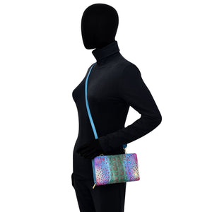 Mannequin dressed in a black bodysuit with a blue stripe and holding an Anuschka Organizer Wallet Crossbody - 1149 with RFID protection.