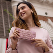 Load image into Gallery viewer, A woman in a pink sweater, smiling and holding a Three Fold Wallet - 1150 by Anuschka with RFID protected card slots.
