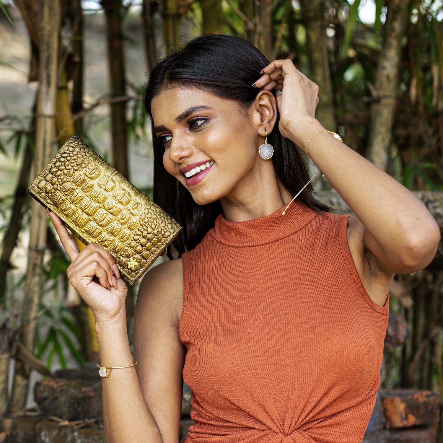 A woman smiling while holding a chic, Anuschka Three Fold Wallet - 1150 outdoors.