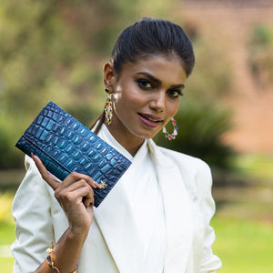 Woman holding a blue Three Fold Wallet - 1150 by Anuschka with RFID protected card slots outdoors.