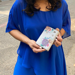 Woman in a blue dress holding an Anuschka Two-Fold Small Organizer Wallet - 1166 with RFID protection.