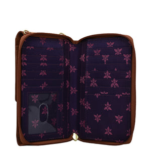 Open empty Anuschka crossbody phone case with a floral pattern interior and pockets.