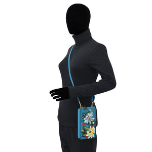 Mannequin wearing a black balaclava, grey jacket, and gloves holding a floral-patterned blue Anuschka Crossbody Phone Case - 1173 with an RFID card holder.