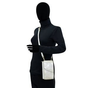 A mannequin dressed in a black bodysuit with an Anuschka genuine leather white Crossbody Phone Case - 1173 over its shoulder.