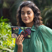 A woman holding an Anuschka Accordion Flap Wallet - 1174 with RFID protection outdoors.