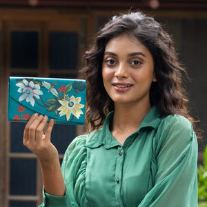 A woman in a green shirt holding a Anuschka Accordion Flap Wallet - 1174 with RFID protection.