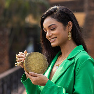 Woman smiling while looking at a Anuschka Round Coin Purse - 1175 featuring hand-painted artwork.