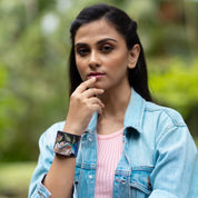 A woman in a denim jacket with antique hardware, pondering outdoors wearing an Anuschka Painted Leather Cuff - 1176.