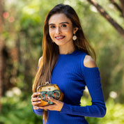 Woman in a blue dress holding an Anuschka Clasp Pouch With Key Fobs - 1177 outdoors.