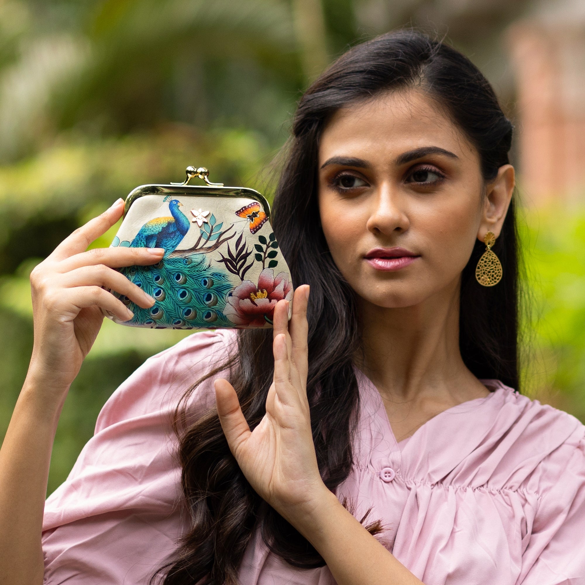 A woman holding a colorful Clasp Pouch With Key Fobs - 1177 by Anuschka with a nature-inspired design.