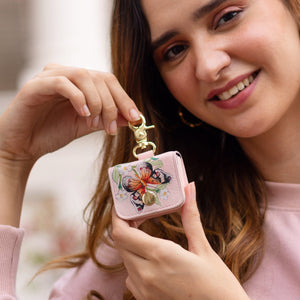Woman smiling and displaying a small, floral printed, leather Anuschka Airpod Pro Case - 1179.