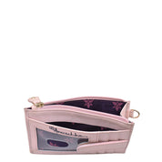 A pink, genuine leather wristlet with an open zipper reveals a purple lining adorned with a floral pattern. The Anuschka Card Holder with Wristlet - 1180 features multiple RFID protected card holders and an ID window showcasing the same floral design.