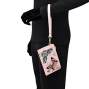 A person with a black outfit holds a Card Holder with Wristlet - 1180 by Anuschka, adorned with floral and butterfly embroidery.