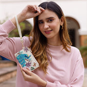 Woman holding an Anuschka Card Holder with Wristlet - 1180, standing outdoors.