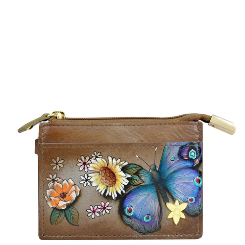 The Anuschka CARD CASE - 1183 is a small brown genuine leather wallet with a zipper, adorned with vibrant hand-painted floral designs and a striking blue butterfly.