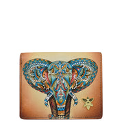 Anuschka's Card Organizer Wallet - 1184 is crafted from genuine leather and showcases a vibrant, intricate hand-painted elephant face design on the front, complemented by a delicate small gold flower embellishment in the bottom right corner.