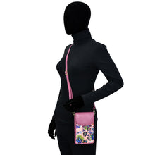 Load image into Gallery viewer, Mannequin displaying a black outfit with a pink floral Anuschka fabric with leather trim cell phone crossbody wallet featuring RFID protection.
