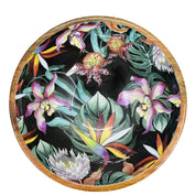 Decorative round tray featuring a colorful floral and botanical enamel inlay on a black background by Anuschka.