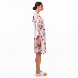 Woman standing side profile wearing a floral Anuschka robe and white sandals, embodying relaxation and self-care.