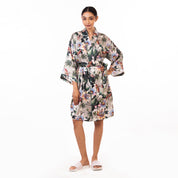 Woman in a silky floral Anuschka robe - 3343 standing against a white background.