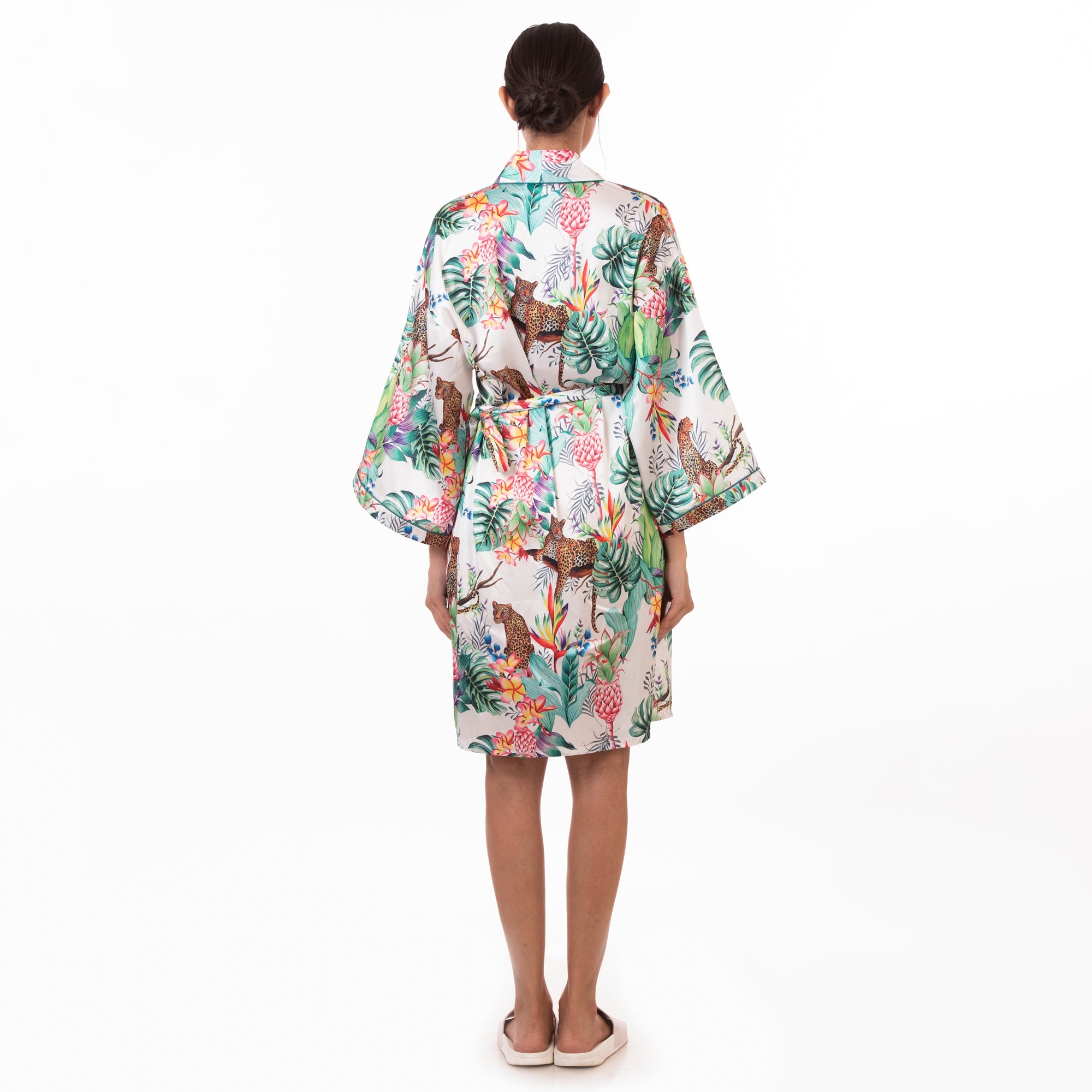 A person standing with their back to the camera, wearing an Anuschka silky robe with a floral print.