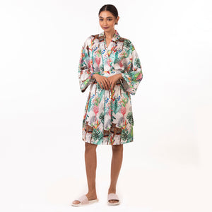 A woman modeling a silky floral Anuschka robe and white sandals against a white background, perfect for a self-care spa day.