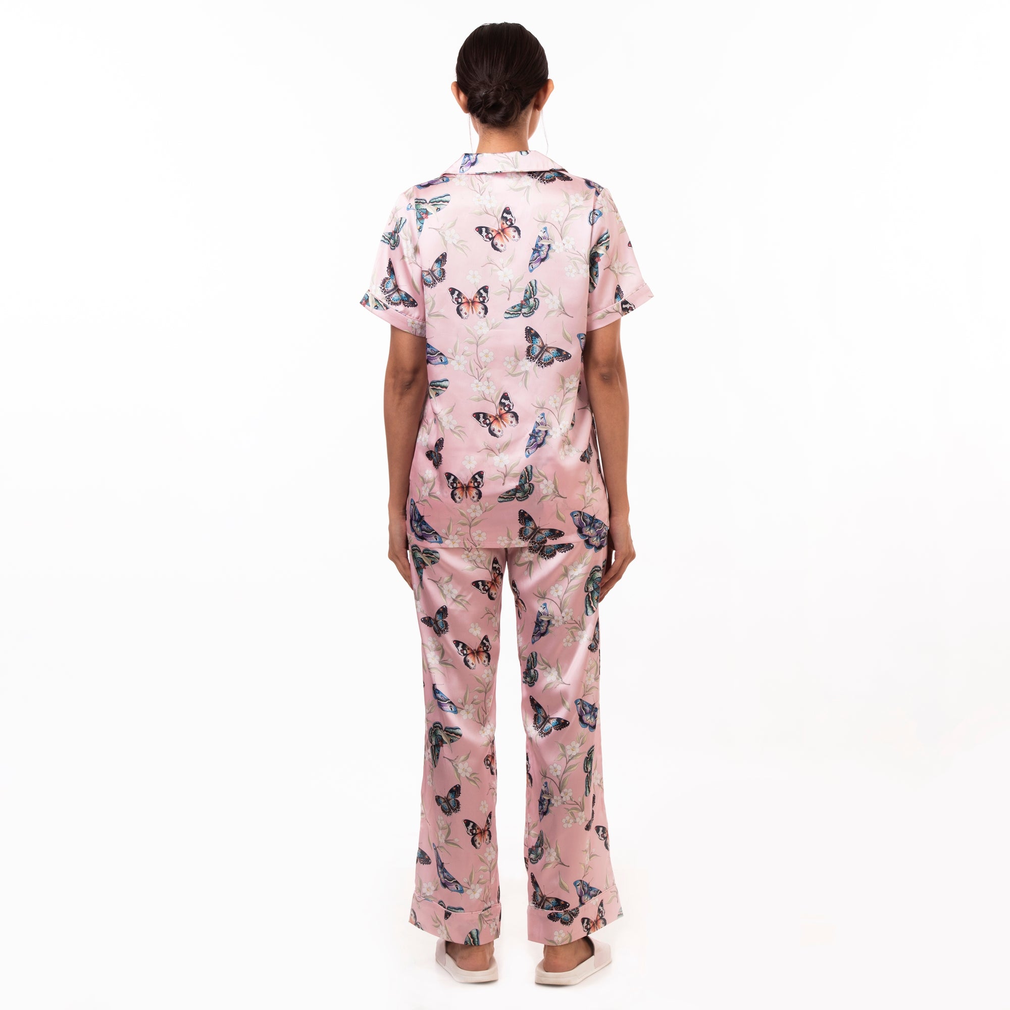 Woman standing with her back to the camera wearing an Anuschka 3344 pajama set in pink scrubs with a butterfly pattern.