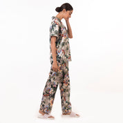 Woman in an Anuschka floral pajama set - 3344 looking downwards while standing against a white background.