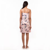 Woman standing facing away from the camera, wearing a pink floral Slip Dress - 3346 from Anuschka with adjustable shoulder straps.