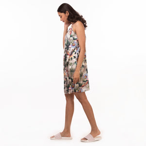 A woman in a chic Anuschka slip dress made of recycled polyester walking to the side against a white background.