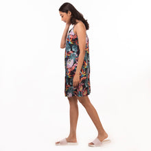 Load image into Gallery viewer, A woman in an Anuschka delicate floral slip dress (3346) and slippers walking to her right with her head down.
