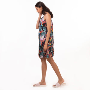 A woman in an Anuschka delicate floral slip dress (3346) and slippers walking to her right with her head down.