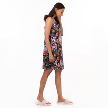 Load image into Gallery viewer, A woman in a delicate Anuschka slip dress adorned with prints stands sideways with her head bowed.
